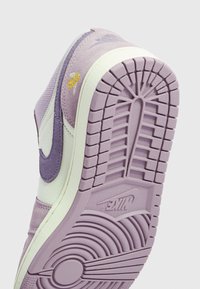 Semelle de basket Nike violet clair et blanc avec motif de bande de roulement détaillé et logo Nike visible sur la semelle extérieure en caoutchouc violet.