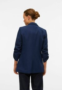 Navy blue blazer with a tailored fit, notch lapels, and rolled sleeves. Made from smooth fabric, featuring a clean, structured design.