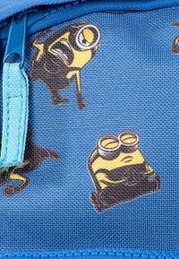 Tela azul con dibujos de los Minions en diversas poses. El diseño incluye una cremallera azul contrastante. Superficie texturizada con patrones juguetones.