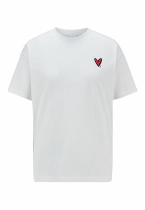 Witte T-shirt met korte mouwen en een klein rood hartvormig plakplaatje met zwarte rand op de linkerborst.