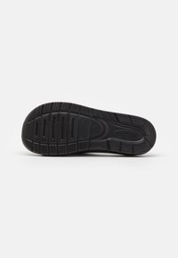 Svart sneakersula med texturerat gummi, utrustad med fåror för grepp och ett slätt centralt område. Hållbar och flexibel design för komfort.