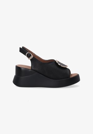 Sorte perforerede wedge sandaler med slingback-design, en rund metalaccent og en glat, mørk sål. Brun indersåling.