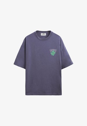Lilla, oversized T-skjorte med korte ermer, med en liten grønn slange og stilisert tekstgrafikk på venstre bryst.
