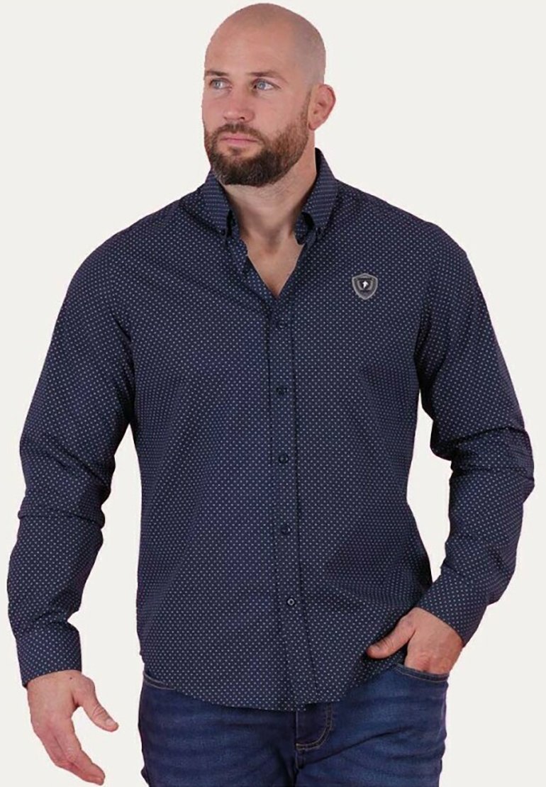 Chemise boutonnée bleu marine avec des pois blancs, à manches longues, et un emblème sur la poitrine. Tissu lisse avec un col et des poignets structurés.