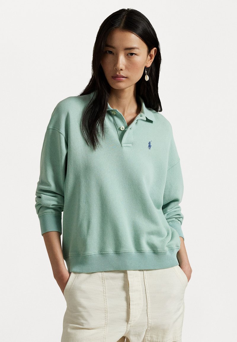 Sweatshirt polo verde mentă cu guler și manșete ribbed, având un mic logo albastru pe piept și o croială relaxată.