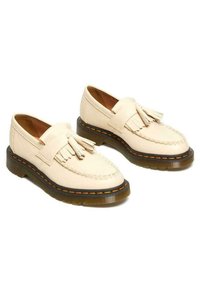 Mocassini bianchi in pelle con dettaglio a nappina, cuciture gialle e suole trasparenti marroni. Punta arrotondata e design slip-on.
