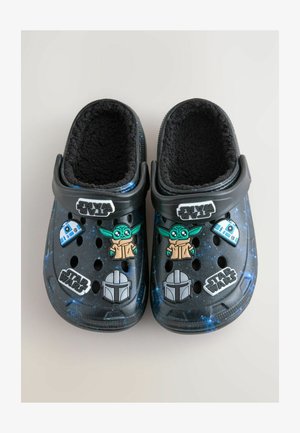 Sorte slip-on klipklapper med blødt sort for og forskellige Star Wars-tema dekorationer, herunder figurer og logoer, i et rum mønster.