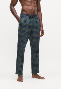 Zeleno-námornické kárované tepláky s nastaviteľným pásom, bočnými vreckami a pohodlným strihom, vyrobené z mäkkej tkaniny pre pohodlie.