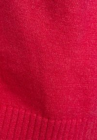 Tejido de punto rojo con una textura suave, que presenta un dobladillo acanalado en la parte inferior. El tejido tiene un aspecto ligeramente jaspeado.