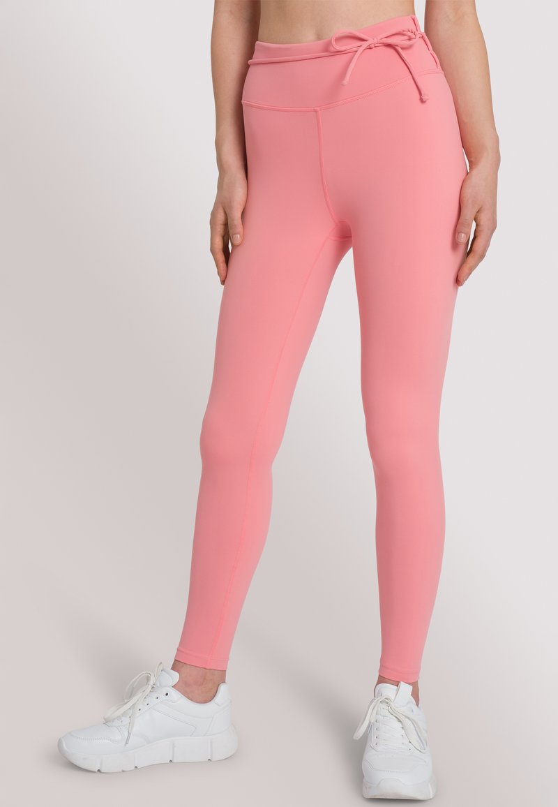 Roze leggings met een hoge tailleband en een trekkoord, gemaakt van soepel, rekbaar materiaal. Heeft contrasterende naden en een aansluitend ontwerp.