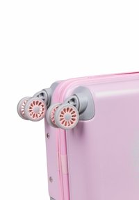 Rosa hård resväska med en glänsande yta, med grå handtag och rosa hjul med ett blommönster. Dragkedjestängning längs ena sidan.