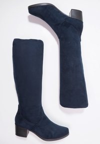 Navy blue suede knee-high boots with a block heel, featuring a smooth texture and curved design. Straight and clean lines on the shaft.