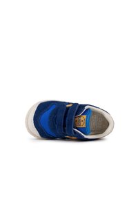 Zapatilla azul con correas de velcro, materiales de ante y tela, puntera redonda, suela texturizada y logotipo en amarillo en el costado.