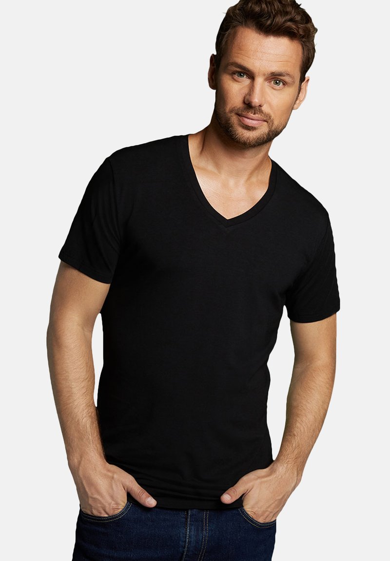 Zwarte V-hals t-shirt gemaakt van zachte katoen. Aansluitend ontwerp met korte mouwen en een gladde textuur. Draagt met de handen in de zakken.