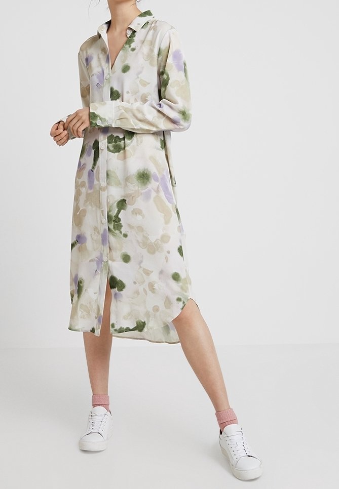 Lång knäppklänning i ett lätt, genomskinligt tyg med ett abstrakt, akvarellmönster i grönt och lavendel på en ljus bakgrund.