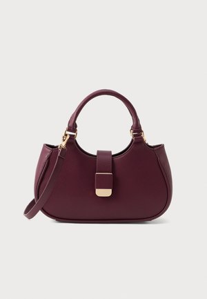 Burgundy handbag made of textured synthetic material with a gold-toned clasp, rounded shape, top handle, and detachable shoulder strap.