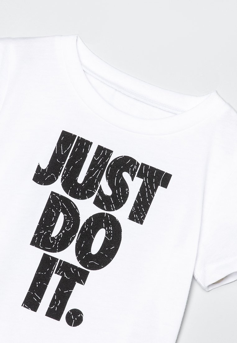 Biała koszulka z bawełny z odważnym czarnym napisem "JUST DO IT" w teksturowanym wzorze, okrągłym dekoltem i krótkimi rękawami.