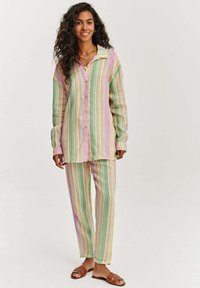Pruhovaný set na voľný čas v pastelových farbách, pozostávajúci z košele na gombíky s golierom a zodpovedajúcich nohavíc. Materiál vyzerá jemne a textúrovane.