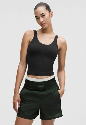Sort cropped tanktop parret med mørkegrønne sports shorts, der har en struktureret talje og sidelommer. Glat stof med en tætsiddende pasform.