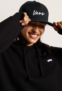 Mustahuppari, jossa on kiristysnyörit ja pieni valkoinen skeittikuvasto. Musta lippis, jossa on valkoinen brodeerattu "Vans"-logo.