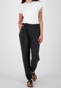 Svarta mönstrade joggerbyxor med knytmidja, med en subtil linjeteckningdesign. Kombineras med en enkel vit t-shirt med kort ärm.