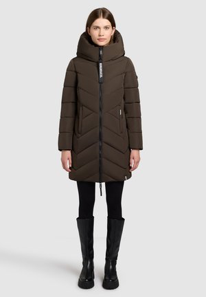 Bruine pufferjack met een hoge kraag, chevronpatroon, rits aan de voorkant en logo-label. Draag het met zwarte leggings en kniehoge zwarte laarzen.
