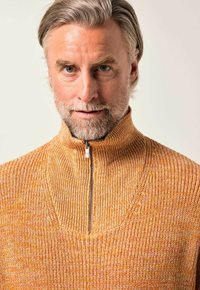 Orangener Strickpullover mit hohem Kragen und halbem Reißverschluss. Verfügt über ein strukturiertes Muster und feine Rippen an Kragen und Saum.