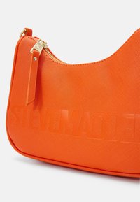 Orange textured handbag with a curved shape, featuring a gold zipper and embossed logo. Smooth material with a sleek finish.
