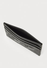 Portefeuille en cuir noir, avec des motifs géométriques en relief, une conception ouverte et une doublure en tissu. Forme compacte, avec plusieurs emplacements pour cartes.