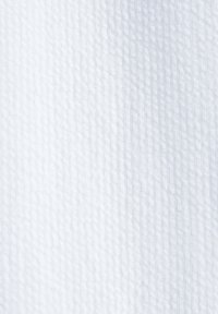 Tissu blanc texturé avec un motif en grille subtil et des rayures verticales discrètes, montrant les détails du textile tissé.