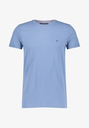 T-shirt bleu clair à manches courtes et col rond, avec petit logo drapeau Tommy Hilfiger sur le côté gauche de la poitrine et détail de col intérieur marqué.