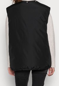 Schwarze gepolsterte Weste mit runder Halslinie, Druckknöpfen hinten und elastischem Saum. Das Material wirkt glatt mit einem leichten Glanz.