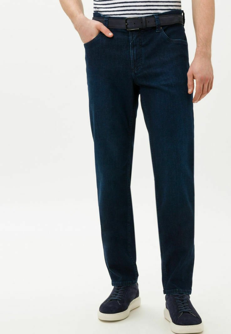 Donkerblauwe denim broek met een rechte pasvorm, voorzien van voorzakken en een riem. Gepaard met donkere sneakers en een gestreefd shirt.