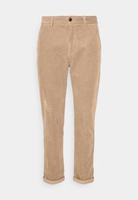 Pantalon en velours côtelé beige avec devant plat, fermeture par un seul bouton et revers roulés. Caractérisé par une texture côtelée verticale.