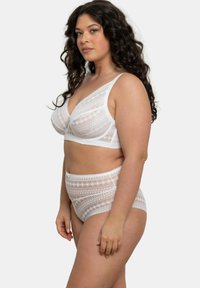 Bralette en dentelle blanche et culotte taille haute avec des motifs géométriques. Tissu transparent avec des bords ondulés et des bretelles réglables.