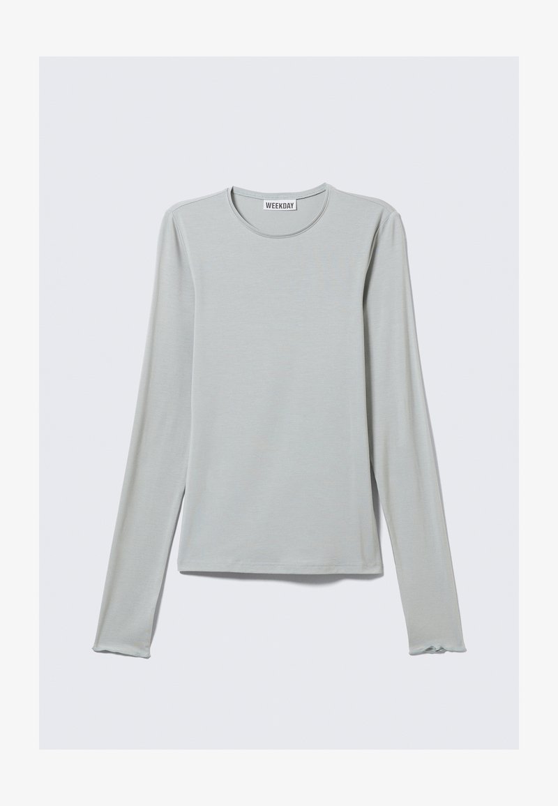 Camiseta de manga larga gris claro confeccionada en tela suave, con escote redondo y puños sutilmente ondulados. Diseño minimalista sin estampados.