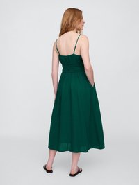 Vestido verde, sin mangas, de longitud media con un cuerpo fruncido, tirantes finos y bolsillos laterales. Tejido suave y ligero.