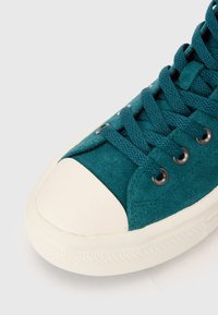 Türkise Wildledersneaker mit weißem Gummi-Zehenschutz und Sohle. Verfügt über flache Schnürsenkel, die durch metallische Ösen gefädelt sind. Texturierte Oberfläche sorgt für Grip.