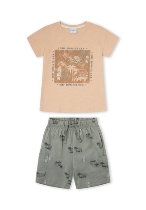 Camiseta beige de manga corta con estampado de tabla de surf, palmera y furgoneta, combinada con pantalones cortos grises con patrones a juego de surf y furgoneta.