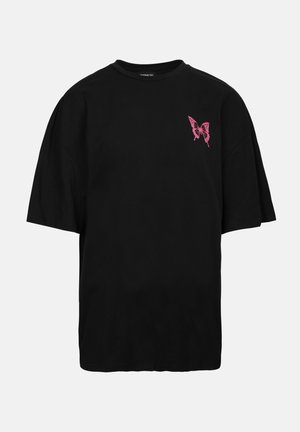 Schwarzes, übergroßes T-Shirt mit kurzen Ärmeln, das ein pinkes Schmetterlingsmotiv auf der linken Brustseite zeigt. Aus Baumwollmaterial, Rundhalsausschnitt.