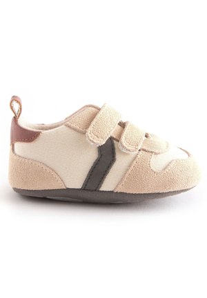 Chaussure souple beige et crème pour tout-petit avec deux brides Velcro, détail latéral gris foncé, languette de talon marron et semelle texturée.