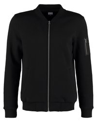 Veste bomber noire en tissu mélangé coton, dotée d'une fermeture éclair, de poignets côtelés et d'une poche zippée sur la manche gauche.