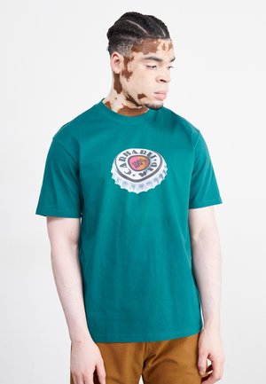 Camiseta de algodón verde con un gráfico de una tapa de botella y el texto "CARHARTT 1600" acompañado de estrellas. Mangas cortas; corte relajado.