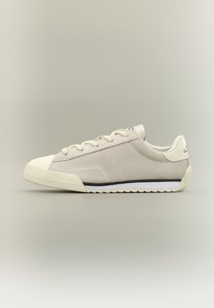 Sneaker beige in suede dal profilo basso con punta in gomma color bianco sporco, chiusura con lacci e suola bianca con dettaglio a striscia nera.