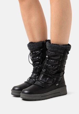 Bottes de neige noires avec une tige matelassée brillante, des lacets réglables, un revers gris duveteux et une semelle en caoutchouc texturée. Logo décoratif sur le côté.