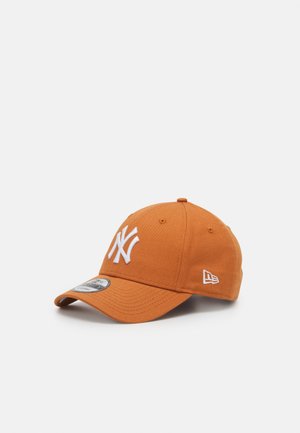 Casquette orange avec logo NY brodé en blanc, visière incurvée, sangle ajustable et étiquette de logo sur le côté. Le tissu semble texturé et durable.