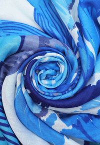Foulard blu a motivo, realizzato in tessuto leggero. Il design presenta diverse sfumature di blu e bianco, disposte in una spirale. Tessuto morbido.