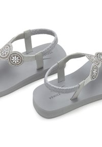 Grijze flip-flops met een platte zool, voorzien van decoratieve grijze en zilveren kralenaccenten en een gestructureerde band voor extra grip.
