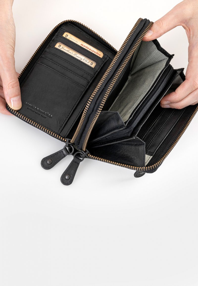 Portafoglio in pelle nera con chiusura a zip. Presenta diversi slot per carte, scomparti e una fodera interna a righe. Le linguette della zip sono accentuate in pelle.