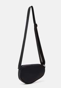 Black crossbody bag with a curved, sleek design made from smooth material. Features an adjustable strap and a zipper closure.